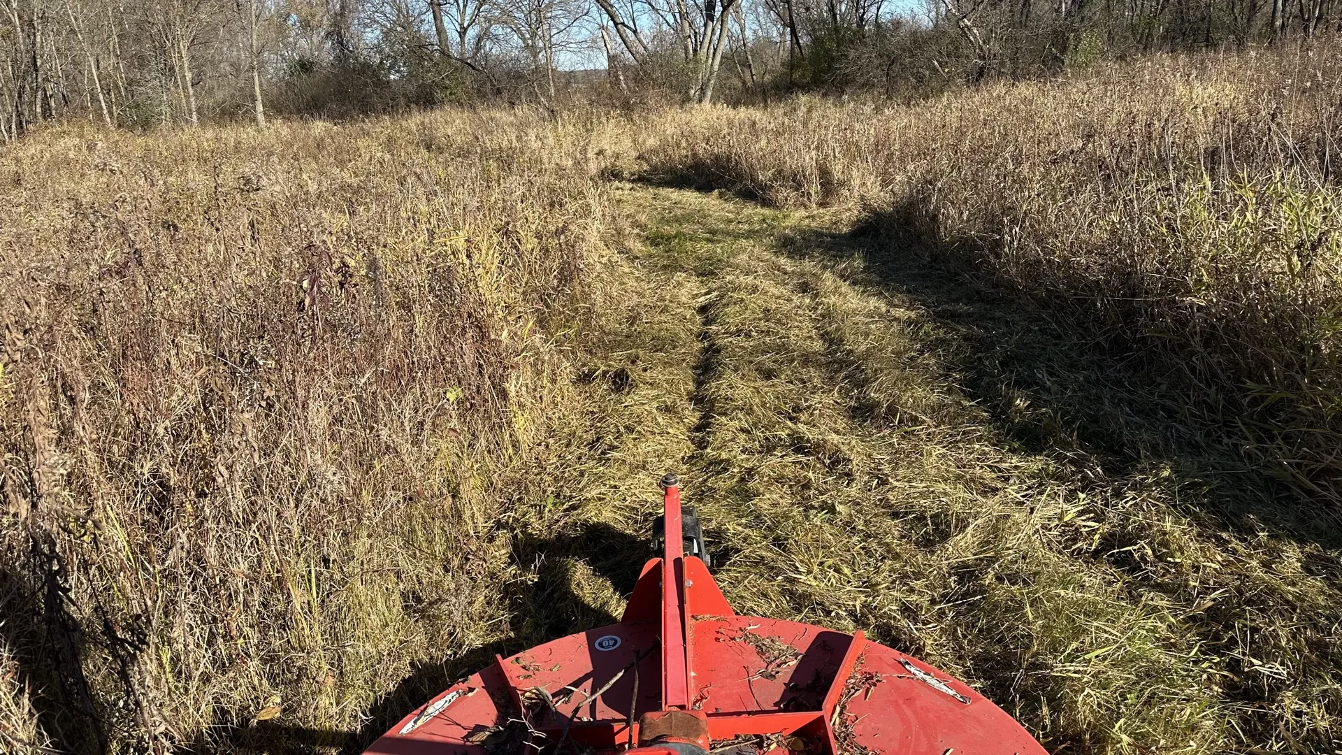 Bush hog mower cutting through overgrown field in central Wisconsin